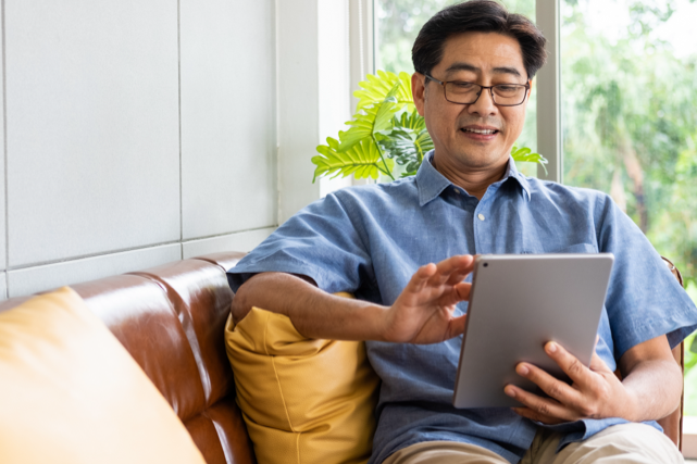 An Asian American man using a tablet device for Telehealth